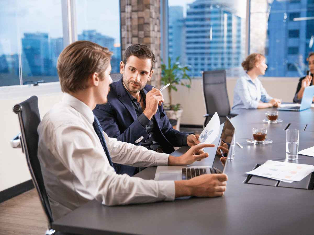 An IT team meeting around a table with laptops